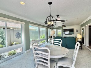 A dining area with a round table, white chairs, a chandelier, and a ceiling fan. - Coral Crest at Frogmore - 3/3 w/ 4-Seat Golf Cart in The Villages - Moultrie Creek (Moultrie Creek, The Villages)