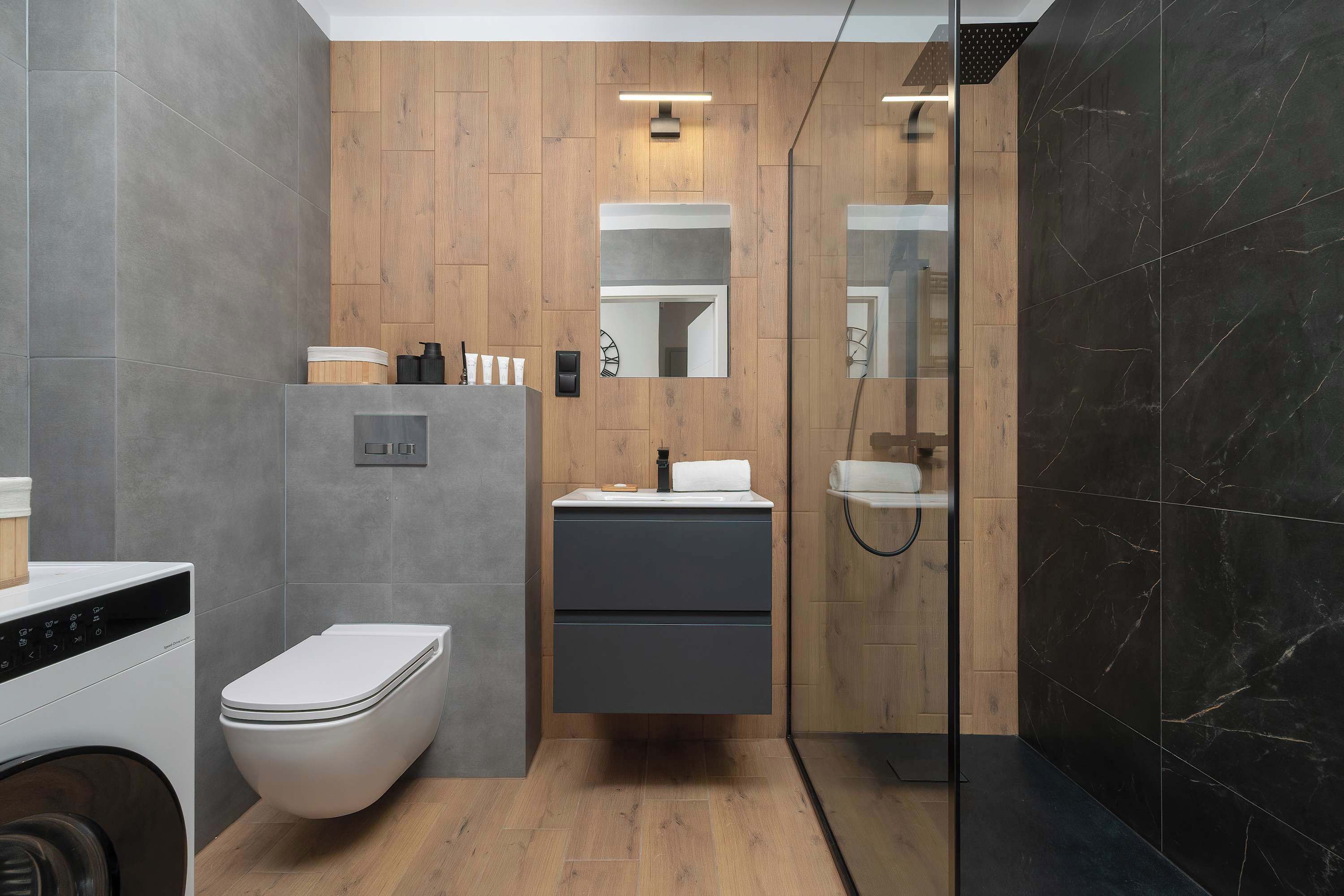 Un baño moderno con inodoro, lavamanos y zona de ducha.