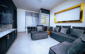 Ein modernes Wohnzimmer mit einer Couch, einem Hocker und einem Fernseher.
