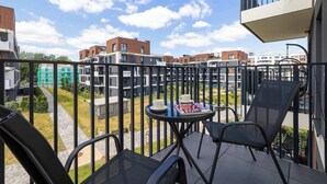 En balkon med et bord og stole, der ud til et boligområde med moderne bygninger.