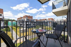 Ein Balkon mit Tisch und Stühlen, mit Blick auf eine Wohngegend mit modernen Gebäuden.