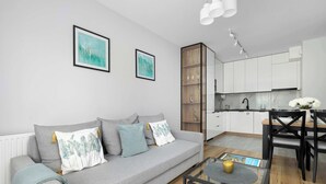 A modern living room with a grey sofa, a glass coffee table, and a dining area with a black table and chairs.