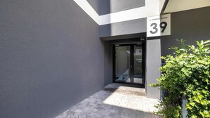 A modern building with a grey facade, a glass door entrance, and a number '39' sign.