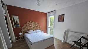 A bedroom with a bed, a chair, a window, a radiator, and a wall with a picture. - L'amirauté pour 4 personnes (La Rochelle)