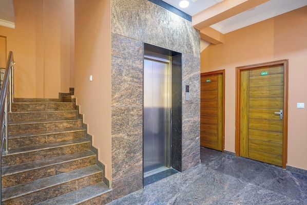 A hotel lobby with a marble staircase, an elevator, and wooden doors. - CollectionO Yeshvantpur Railway Junction (Bangalore)