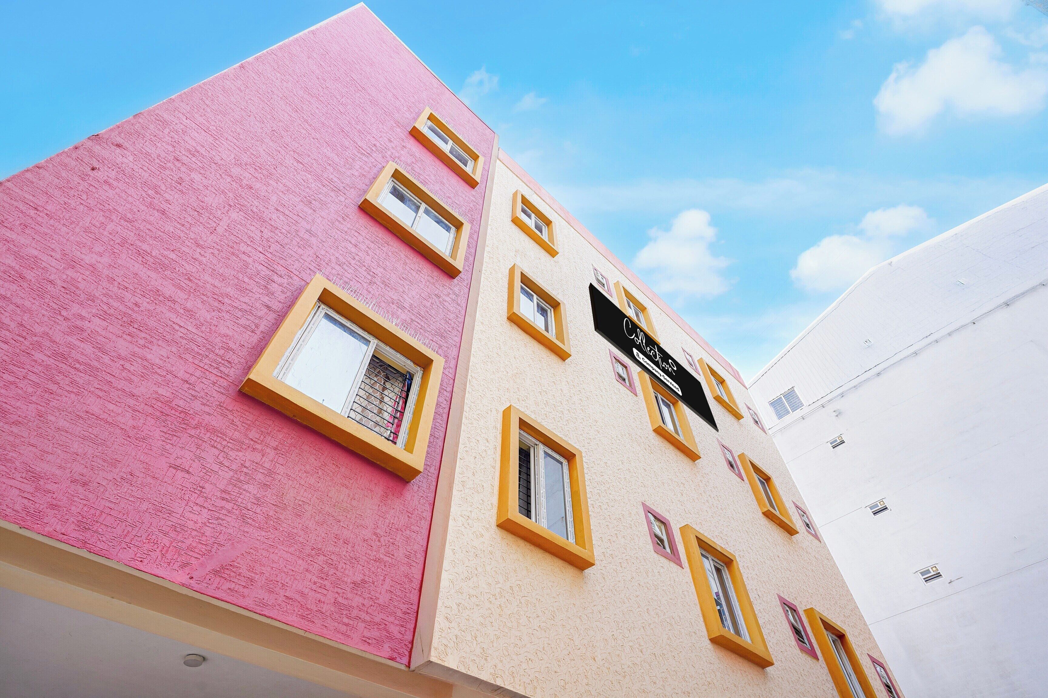 A multi-story building with a pink facade and yellow window frames.