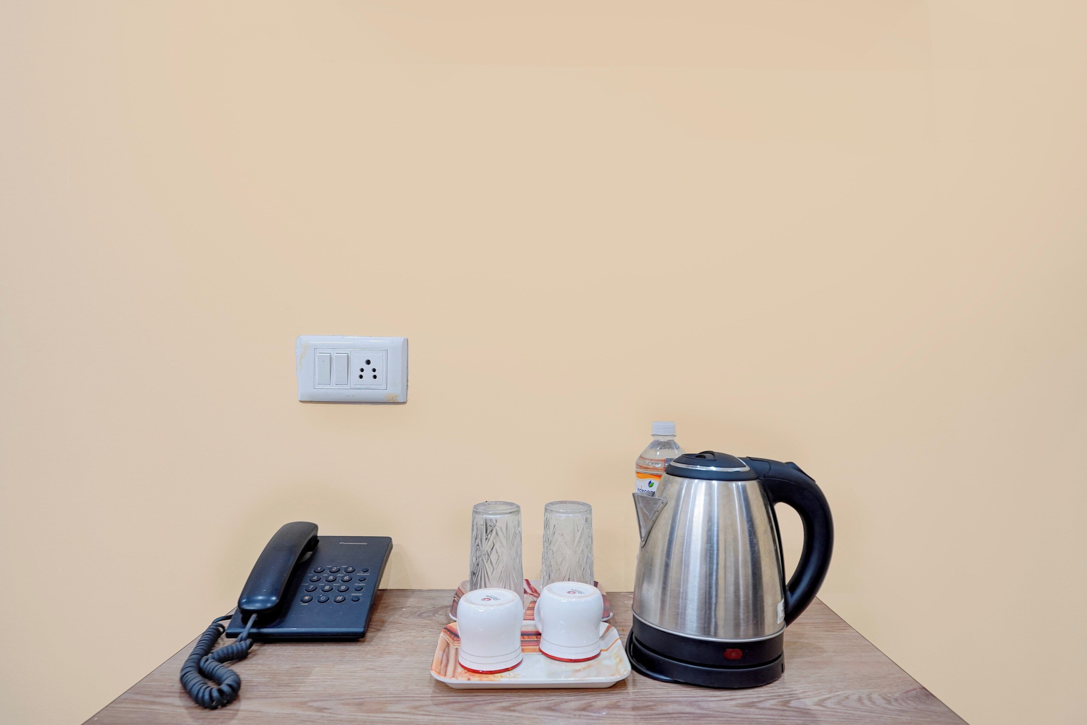 Una mesa de madera con un teléfono, una tetera y dos tazas sobre una bandeja.