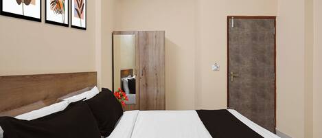 Quarto de hotel com cama, guarda-roupa, porta e obras de arte nas paredes.