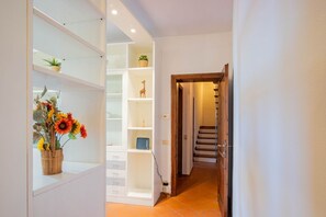 Ein Flur mit einer eingebauten Regallösung, einer Topfpflanze und einer Treppe.