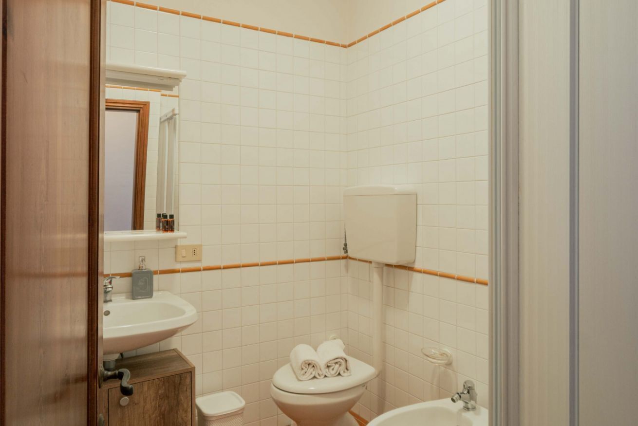 A bathroom with a toilet, sink, and a mirror.