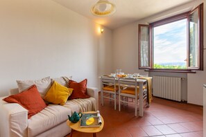 Ein Wohnzimmer mit einer Couch, einem Tisch mit Stühlen, einem Fenster mit Blick und einer Heizung.