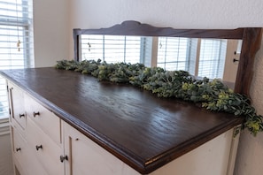 Un armari de fusta amb un mirall i una planta decorativa verda.