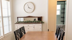 A dining room with a wooden table and black chairs, a white wall clock, and a window with blinds. - This home located in the Temple Historic District has recently been renovated and updated for a luxurious stay, while maintaining the aesthetic historical  vibe. (TEMPLE)