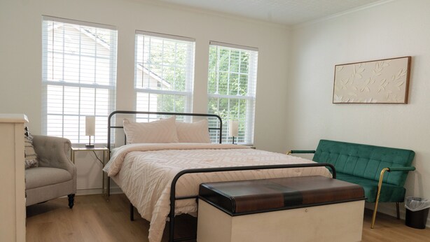 A bedroom with a bed, a green sofa, a chair, and a bedside table. - This home located in the Temple Historic District has recently been renovated and updated for a luxurious stay, while maintaining the aesthetic historical  vibe. (TEMPLE)