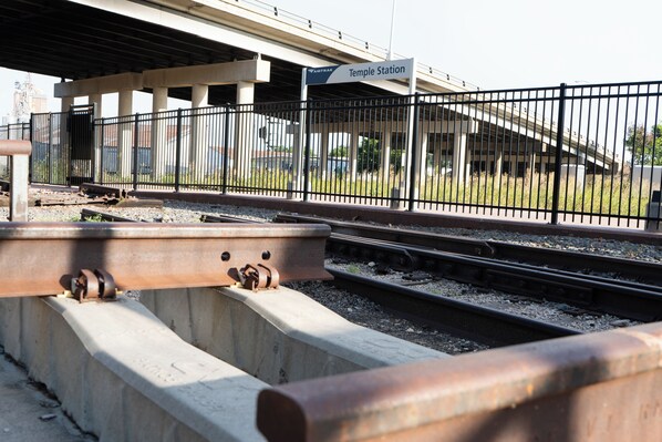 A railway station platform with a sign for 'Temple Station' and a metal fence.