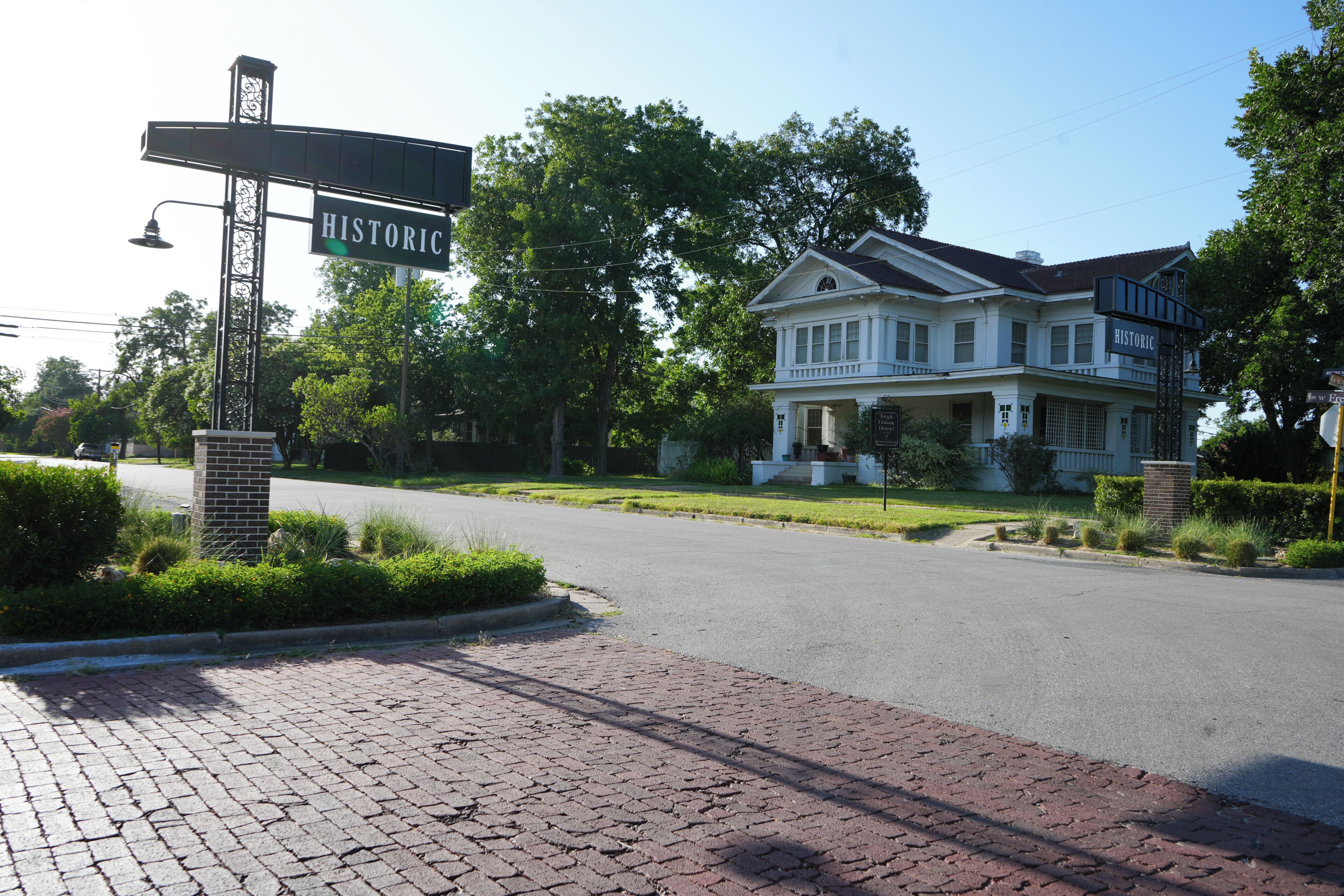 A historic house with a brick driveway and a street sign.