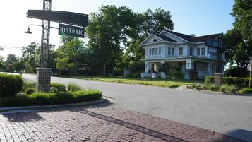 A historic house with a brick driveway and a street sign.