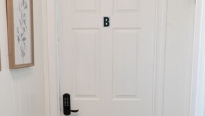 Eine weiße Tür mit schwarzem Türgriff und einem Schild mit dem Buchstaben 'B' darüber.