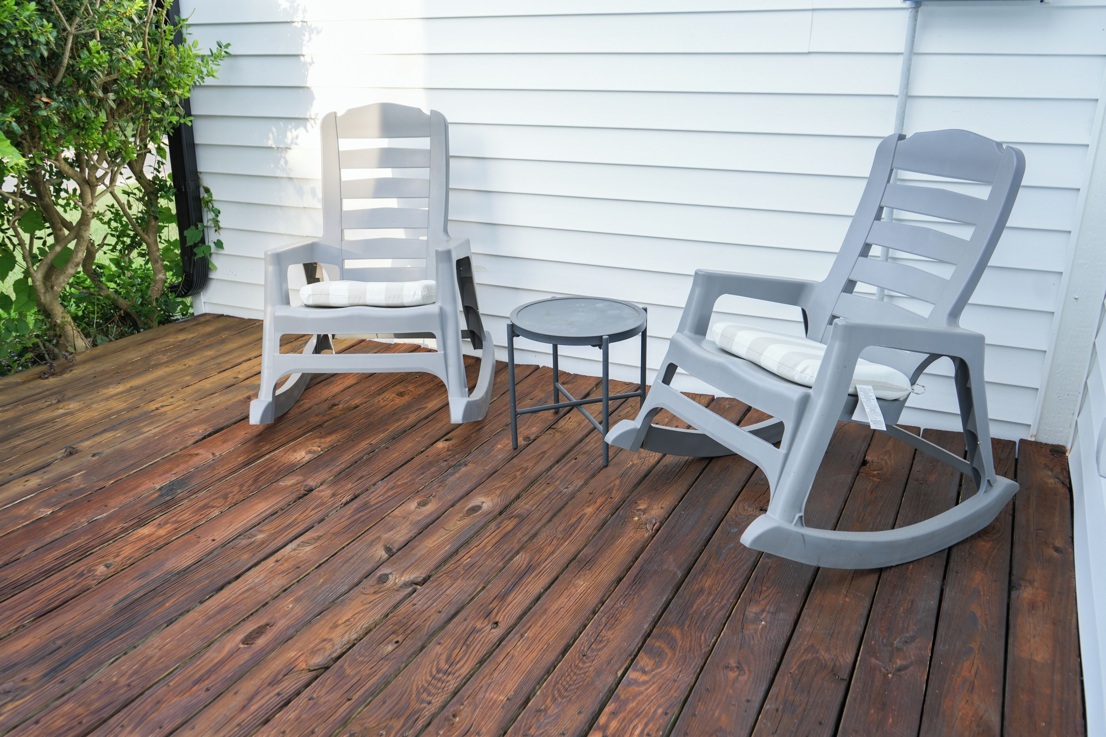 A wooden deck with two rocking chairs and a small table.