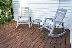 A wooden deck with two rocking chairs and a small table. - Located in the Historic District, you will enjoy the luxury of a fully renovated and relaxing suite. (TEMPLE)