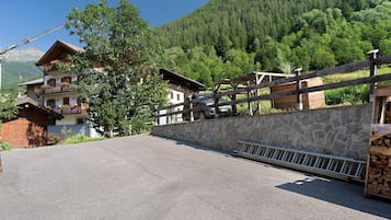 Ein Gebäude mit einer Steinmauer und einem Holzzaun, einer gepflasterten Auffahrt und einer bergigen Kulisse.