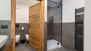 Une salle de bain moderne avec une porte en bois, une douche en verre et un porte-serviettes noir.
