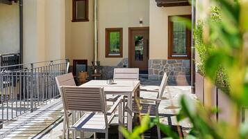 Eine Terrasse im Freien mit Tisch und Stühlen, einer Steinmauer und einer Holztür.