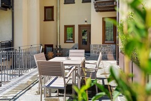 An outdoor patio with a table and chairs, a stone wall, and a wooden door.