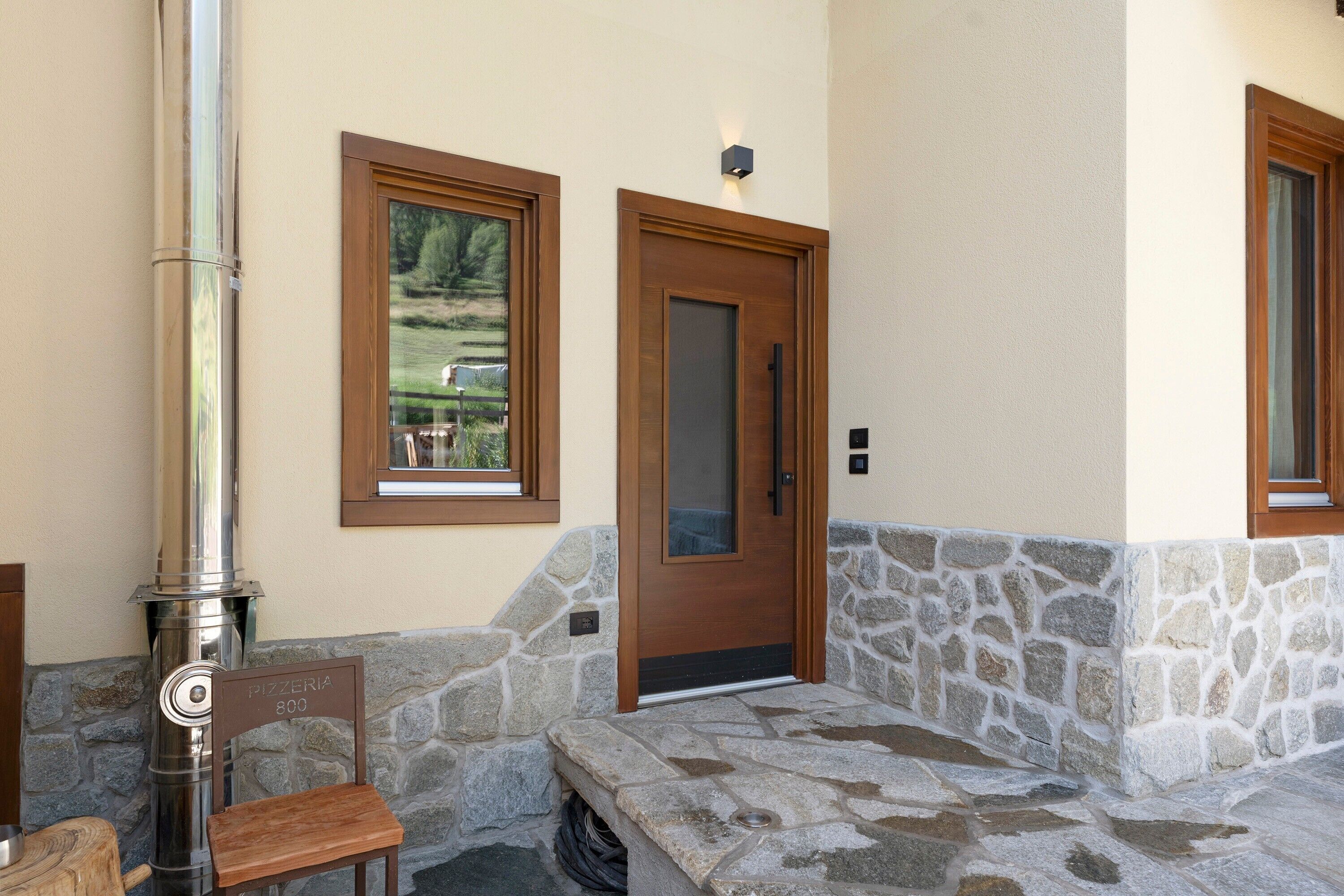 A stone bench, a door, and a window with a view of a landscape.