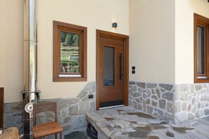 A stone bench, a door, and a window with a view of a landscape.
