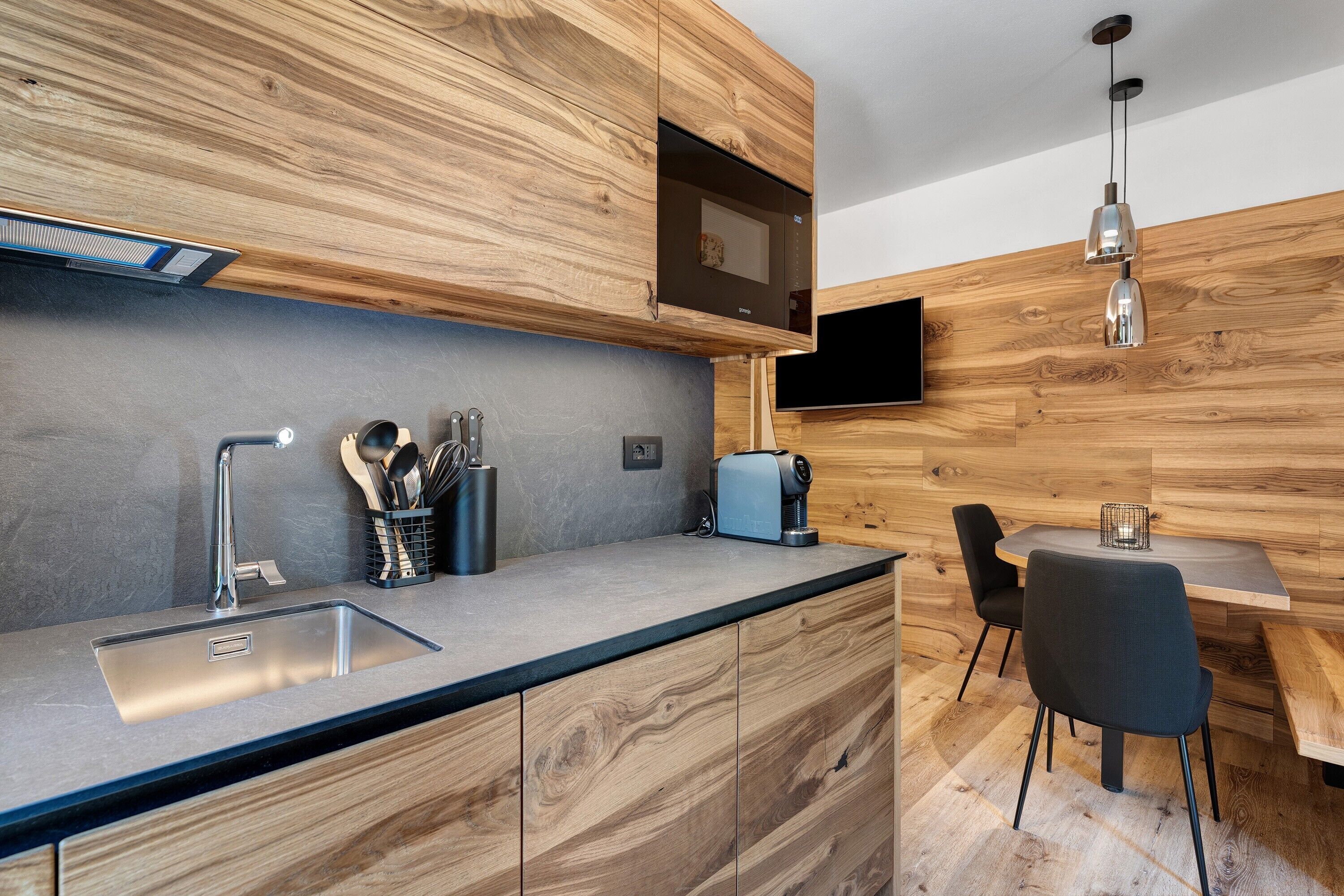 Une cuisine moderne équipée d’une cuisinière intégrée, d’un évier et d’un coin repas avec une table et des chaises.