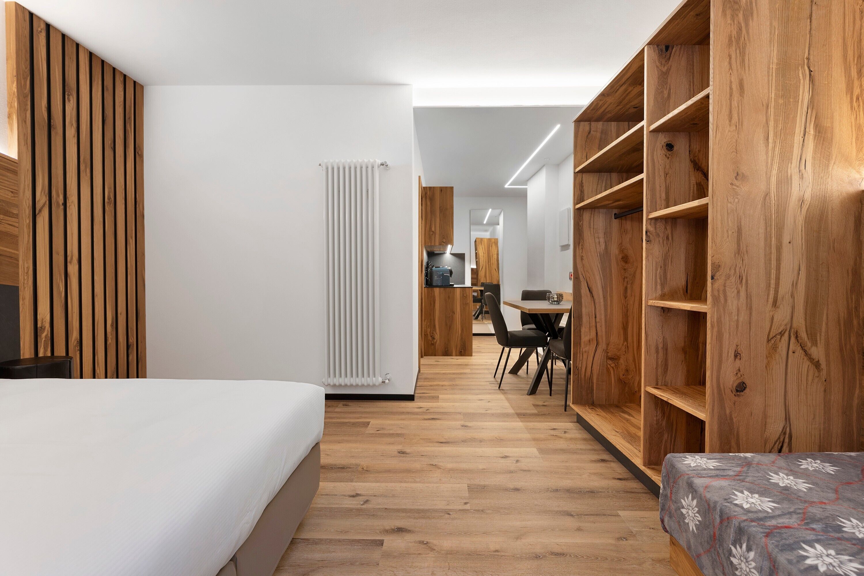 Et moderne hotelværelse med en stor seng, et træskab og et spiseområde med bord og stole.