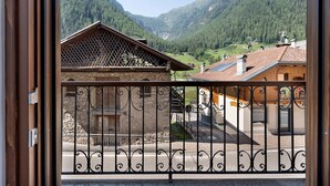 Un balcón con barandilla de hierro forjado con vistas a un paisaje montañoso con edificios tradicionales.