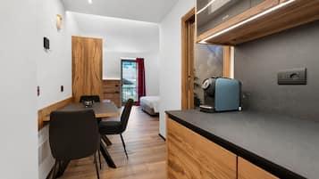 A modern kitchen with a coffee machine, wooden cabinets, and a dining area with a table and chairs.