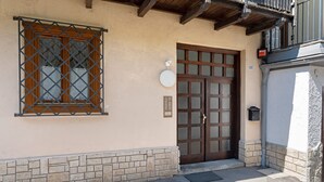 Entrada de un edificio con puerta de madera, ventana con reja metálica y buzón.