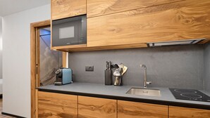 Una cocina moderna con armarios de madera, microondas integrado, cafetera y lavaplatos.