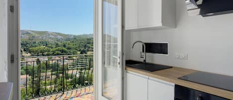 Eine moderne Küche mit Blick auf einen Balkon und eine Berglandschaft.
