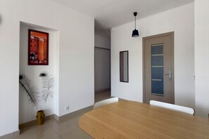 Un intérieur moderne avec une table à manger en bois, un tableau encadré, un miroir et une porte.