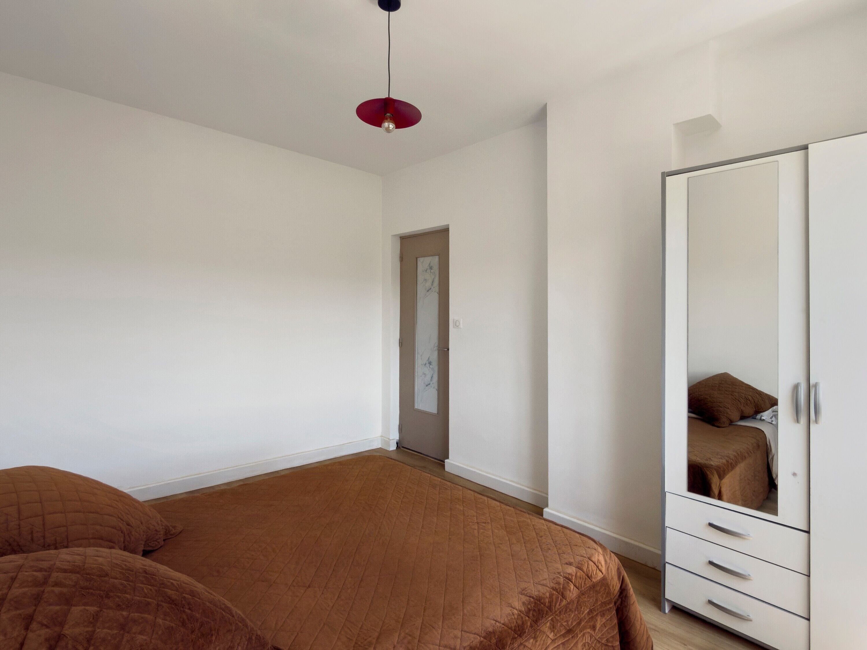 Ein Schlafzimmer mit einem großen Bett, einem Kleiderschrank und einer Tür zu einem anderen Raum.