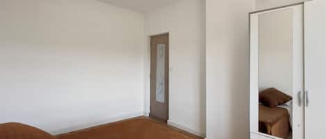Ein Schlafzimmer mit einem großen Bett, einem Kleiderschrank und einer Tür zu einem anderen Raum.