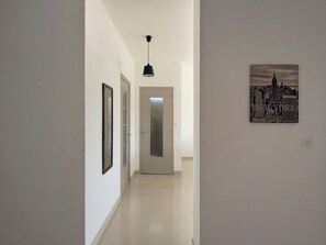 Un couloir avec une porte, un tableau encadré et une suspension.