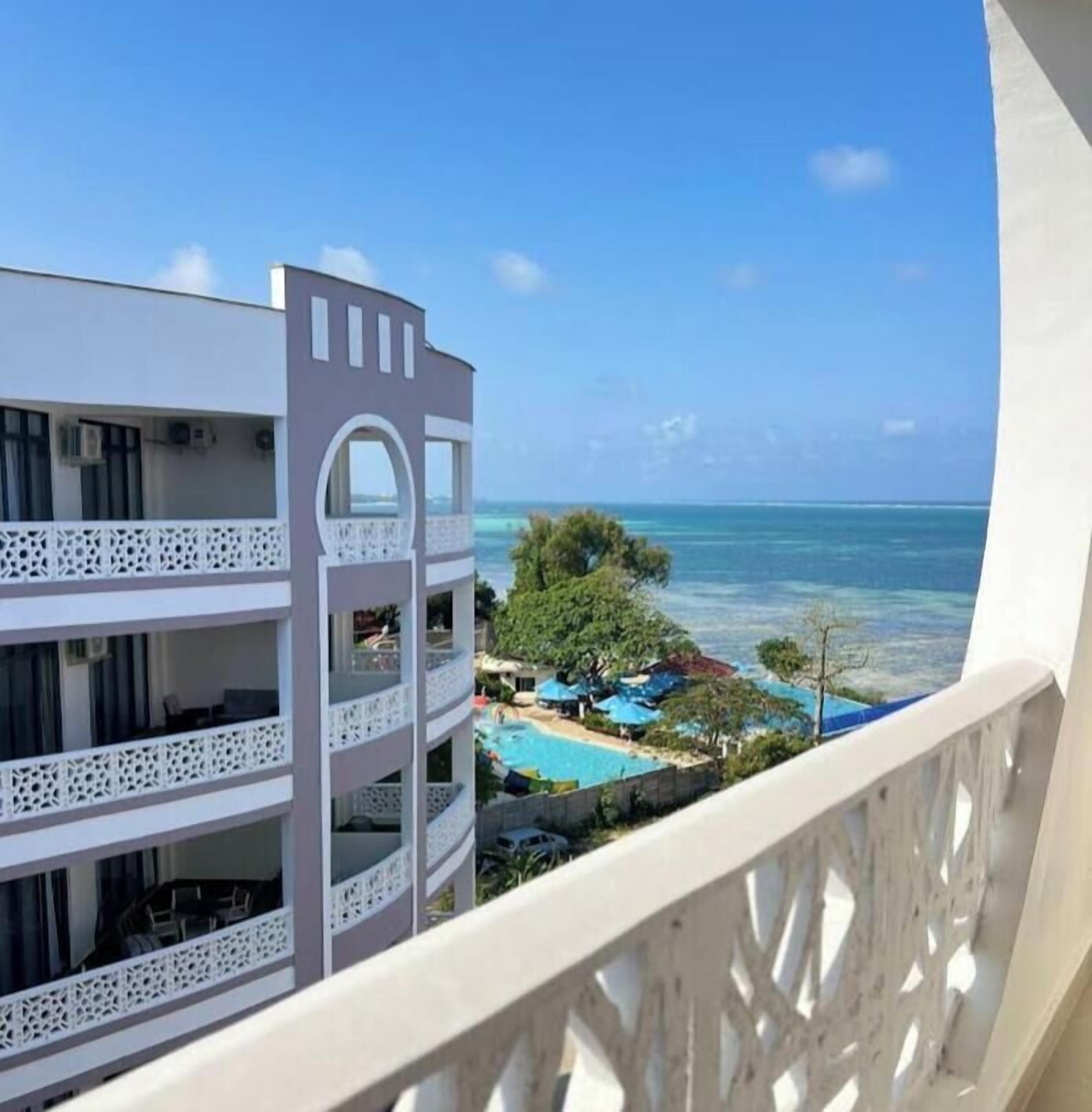 Un balcón de hotel con vista al océano y a la piscina.