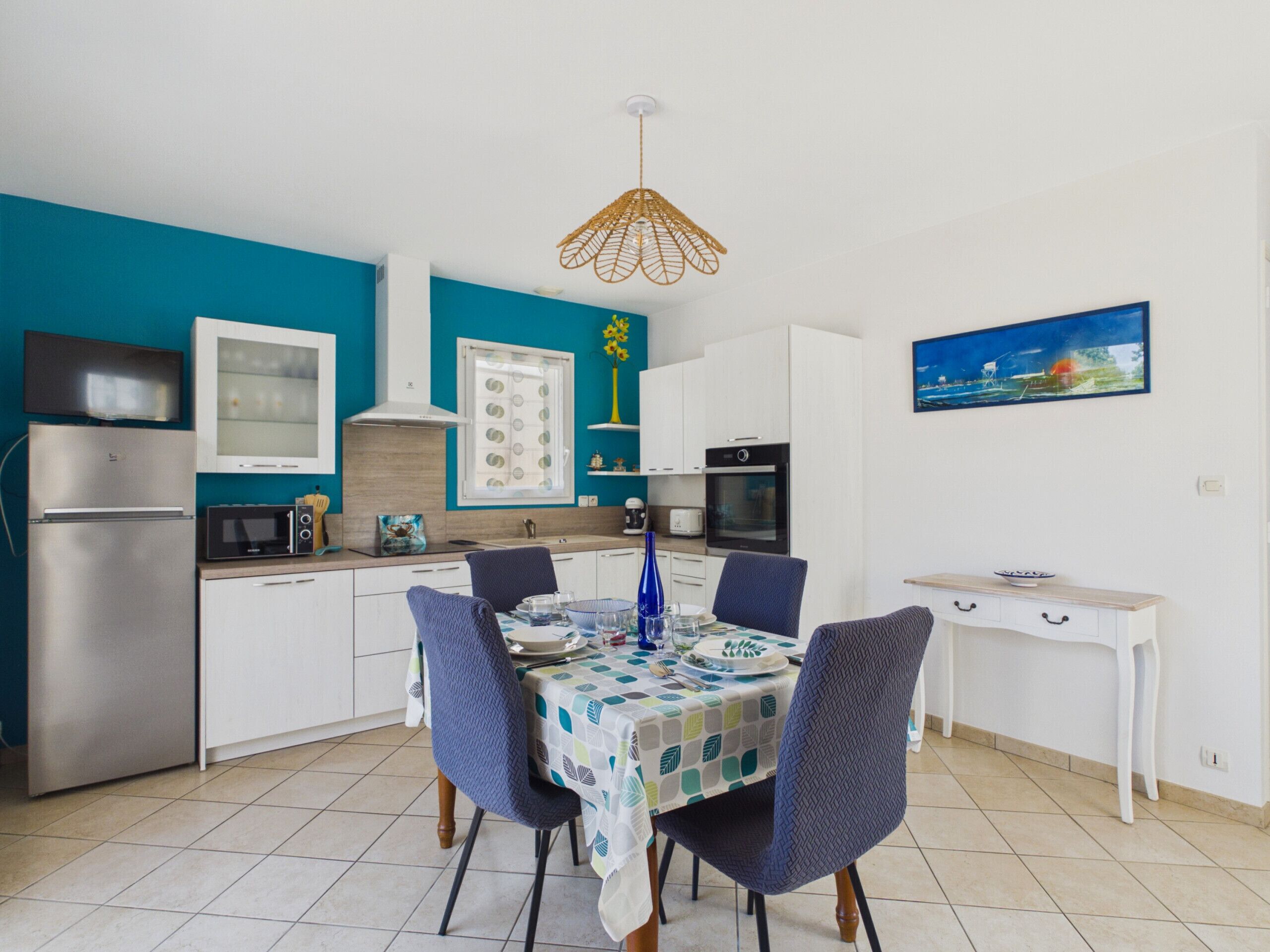 Una cocina compacta con armarios blancos, microondas, estufa y una mesa de comedor lista para cuatro comensales.