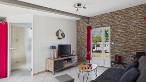 Ein Wohnzimmer mit Steinwand, Fernseher, einer Couch und einer zur Außenseite führenden Tür.
