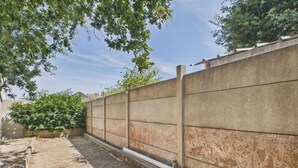 Eine Betonwand mit Entwässerung, umgeben von Grünpflanzen und blauem Himmel.