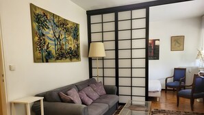 A living room with a sofa, a coffee table, a lamp, a chair, and a patterned rug. - Apartment 'Studio Cannes Gallia' (Cannes)