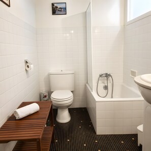 A bathroom with a toilet, a wooden bench, a bathtub, and a shower. - Apartment 'Studio Cannes Gallia' (Cannes)