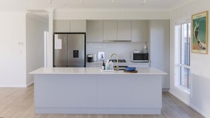 A modern kitchen with a central island, stainless steel appliances, and a large window.