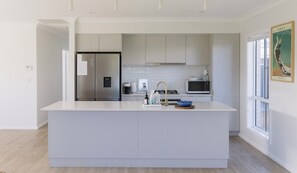A modern kitchen with a central island, stainless steel appliances, and a large window.