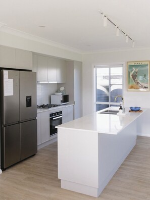 A modern kitchen with a central island, stainless steel appliances, and a large window.